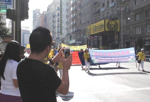 图2：华人在马德里街头观看和拍摄欧洲法轮功学员盛大的游行队伍