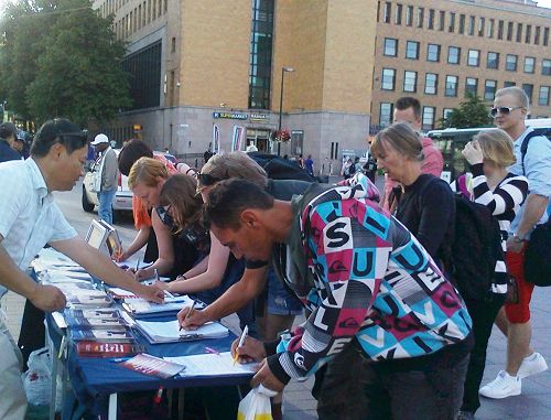 图2-3：赫尔辛基火车站广场上，路人排队签名支持法轮功反迫害