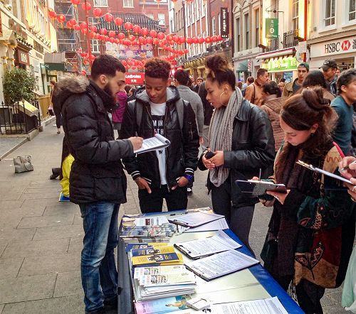 图12：二零一五年十月三日，法轮功学员在伦敦唐人街举行讲真相反迫害活动，许多民众签名支持，其中右一是 SOAS的一位学生。