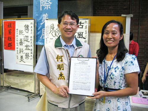 图说2台中市议员何明杰(左)展示了他所签署的“刑事举报江泽民”联署书。