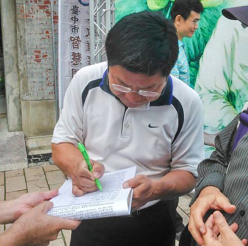 图说3 台中市文化局副局长施纯福正在“刑事举报江泽民”联署书上签名。