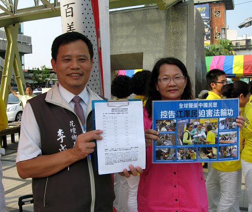 图1：花坛乡乡长李成济（左）在彰化火车站前的声援诉江活动中，签下举报江泽民联署书，并开心地展示。