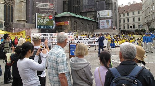 图2：二零一五年九月十九日上午，欧洲法轮功学员在维也纳斯特凡大教堂前广场举行反迫害、声援全球控江集会，主持人在向广场上的民众介绍声援全球控江的重大信息