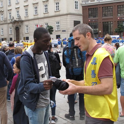 图：2015年9月19日，欧洲法轮功学员在维也纳斯特凡大教堂前广场举行反迫害、声援全球控江集会，意大利法轮功学员安德烈（Andrei）在广场人群中发传单并讲真相