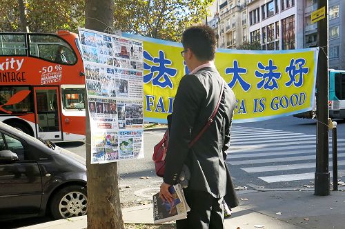 图4-8 ：来巴黎旅游的中国大陆游客经过世界著名的埃菲尔铁塔附近的法轮功真相点时，许多人驻足阅读真相展板，了解真相。