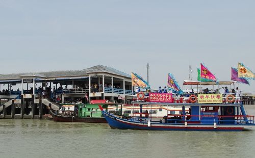 图8-9：二月十三日下午一时，天国乐团团员乘上一艘主要以七彩缤纷的“法轮大法”旗子装饰的双层吉胆岛（Pulau Ketam）环岛游船，开始了当天的环岛演奏。