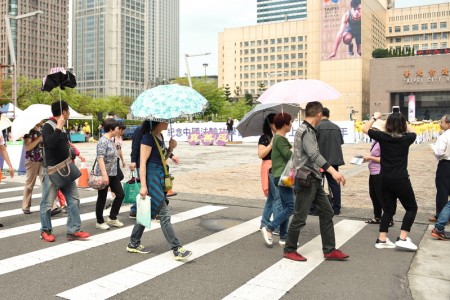 图7-8：法轮功学员在台北市政府前的市民广场举办纪念四二五和平大上访十七周年活动，吸引大陆游客拍摄观看