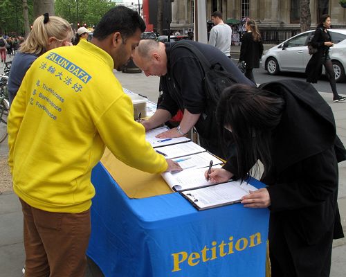 图3：硬件工程师菲利普和女儿在伦敦圣马丁广场签名支持法轮功反迫害