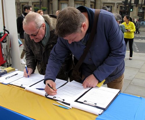 图4：退休图书馆员麦考义（McCoy，左）先生在伦敦圣马丁广场签名支持法轮功反迫害