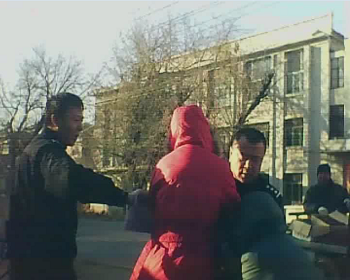 警察周佳佳（左）、张维富（右）正在抢掠祖孙二人手中的物品，老人渐渐倒地。