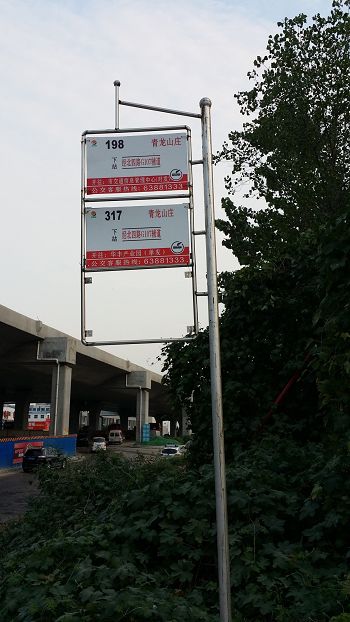 '山庄东大门口的公交站牌，背景为在建的新107国道高架桥'