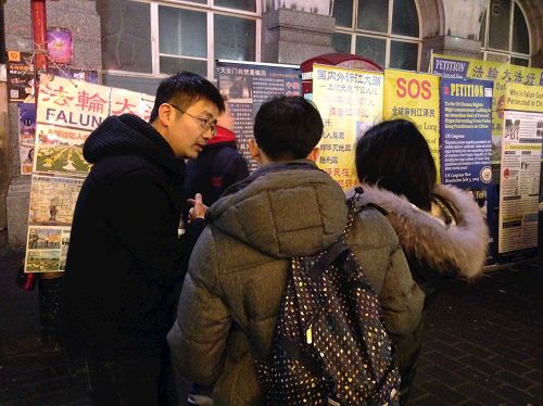 '图2：二零一七年中国新年期间，一对华人青年在伦敦唐人街向法轮功学员了解真相并选择三退'