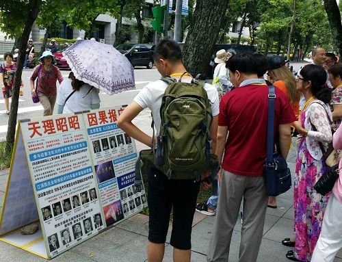 图：国父纪念馆外，大陆游客认真阅读法轮功真相展板