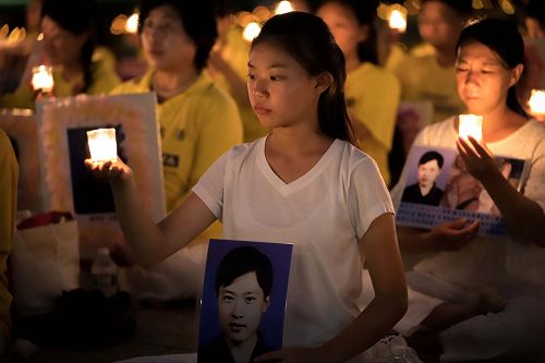 图4：来自辽宁的十六岁女孩徐鑫洋手捧父亲徐大为的遗像。徐大为因为坚持修炼法轮功被中共冤判八年监禁，出狱后十三天离世。