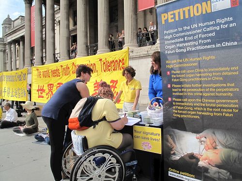 '图20：坐在轮椅上的伦敦女士和朋友签名反迫害'