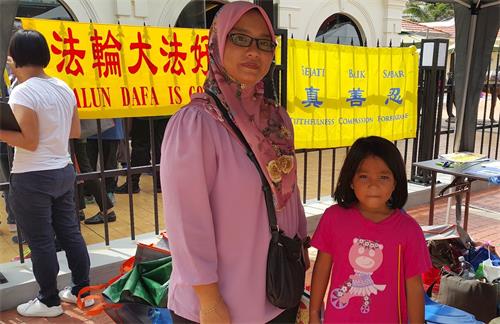 '图6：Nurul Hayati与她的女儿在法轮大法展位留影。Nurul Hayati在了解中共活摘法轮功学员器官的真相后感到震惊。'