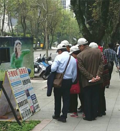 '图：大陆游客在台湾国父纪念馆前认真观看法轮功真相展板'