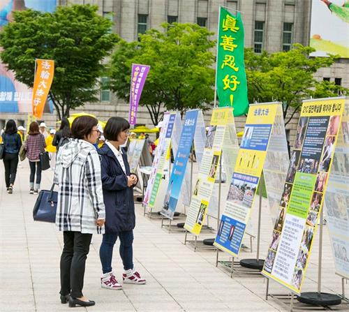 '图10：2018年5月13日，首尔市中心广场举行5·13“世界法轮大法日”庆典，路人驻足观看展板。'