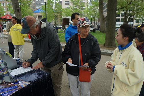 图4：法轮功学员（右）讲真相，游客在反活摘请愿书上签字