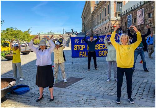 '图1：瑞典学员在位于瑞典国会大厦和皇宫之间的钱币广场上，举办揭露中共迫害、讲真相活动。学员们在演示祥和的五套功法，向过往民众展示法轮大法的美好。'