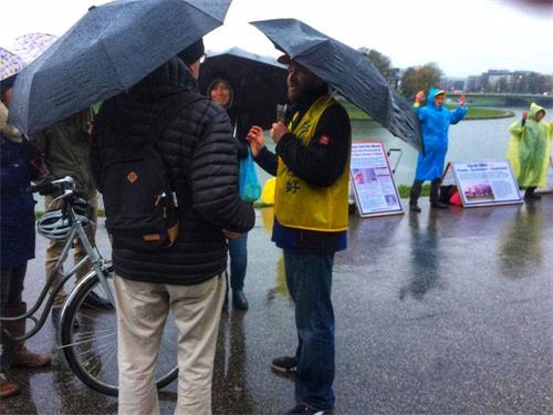 '图7：波兰法轮功学员在雨中向游客讲真相'