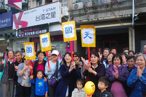 '图7： 一群嘉义市民在民族路上兴奋的举着写着“天国乐团”的广告牌欢迎天国乐团。'