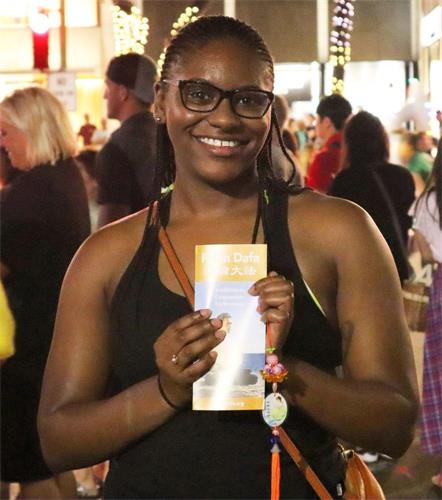 '图3：非裔女孩Nia Liberty手持法轮功传单，表示一定会回去好好阅读。'