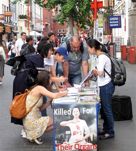 图6：二零一九年六月一日，来伦敦旅游的以色列一家四口人在伦敦唐人街一起签名支持法轮功反迫害，法轮功学员温迪向他们讲真相。