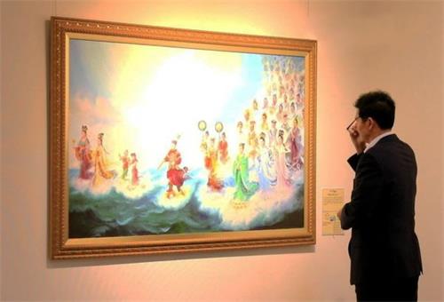 '图2：釜山市民会馆的安贤根（音译）馆长在认真欣赏画作'