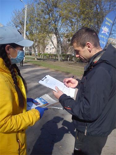 '图1～2：哈尔科夫市民经过炼功场地或和学员交谈，或签名支持法轮功'