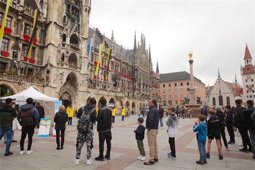 '图1：二零二零年六月十日，德国慕尼黑玛琳广场（Marienplatz）上，民众观看法轮功学员展示功法演示。'