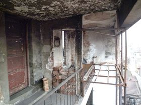 照片左边木门为完好无损的简易房，右边房东简易房大火的残壁，钢架地方是床，木框木门全部烧毁。