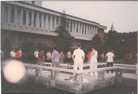 '图二：一九九八年七月二十九日清晨，拍摄于湖南大学图书馆旁的法轮功炼功点，学员们正在炼第二套功法的“腹前抱轮”动作。照片中左下方，照相机拍到一个大光球（法轮）'