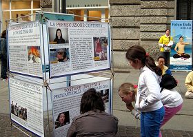 一位意大利母亲蹲在展板前，向她的孩子解释在图片上的迫害真相