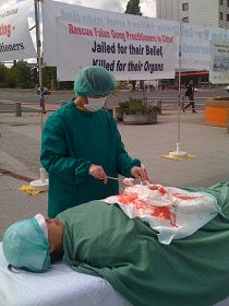 在国际器官移植会议开会地点前，法轮功学员模拟演示中共活摘器官。