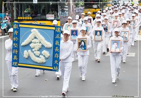 图4：学员穿着净白素服，手捧被迫害致死的大陆法轮功学员照片，圣洁肃穆地行进着
