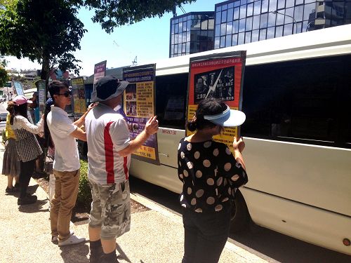 法轮功学员向遊览车上的中国游客展示真相展板