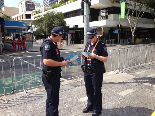 图3：布里斯本二十国集团峰会（G20）峰会期间，澳洲警察在阅读法轮功真相资料。