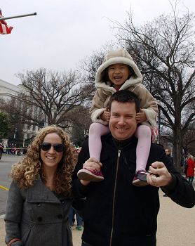 图3：凯瑟琳和先生带着从中国领养的四岁的阿丽斯观看游行