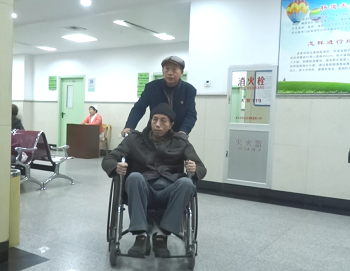 被迫害致瘫的林泽华坐在了轮椅上