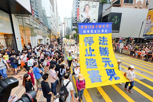 图：十月一日，香港法轮功学员举行“法办元凶、停止迫害”的集会游行，途中许多大陆游客被游行的场面震撼。