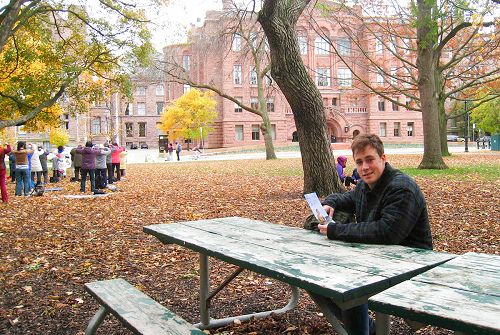 图3：卡尔顿大学的大学生Sam Rubimosi先生坐在长凳上观看法轮功学员的集体炼功。