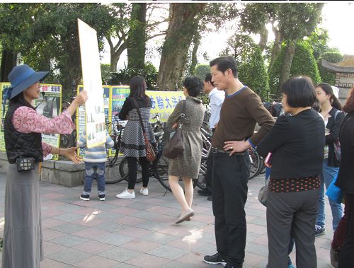 中国大陆游客眼观展板、耳听法轮功学员讲真相。
