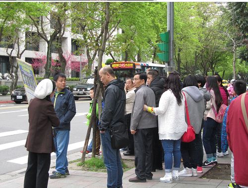 中国大陆游客眼观展板、耳听法轮功学员讲真相。