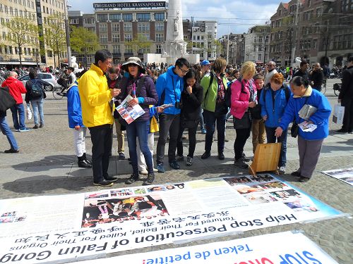 阿姆斯特丹王宫前达姆广场上，游客认真阅读法轮功真相展板