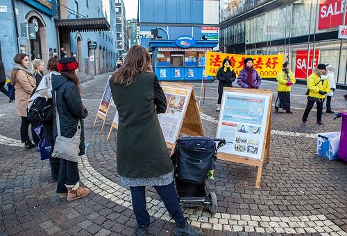 '图1～2：在斯德哥尔摩繁华的闹市区（Hötorget）法轮功学员举办弘法讲真相活动，民众观看真相展板，了解真相。'