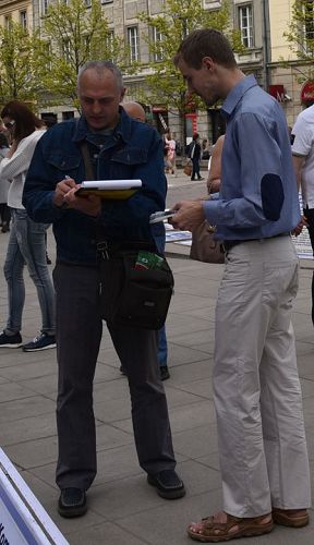 图9：这位中年乌克兰游人（左）含泪签名，表示支持法轮功