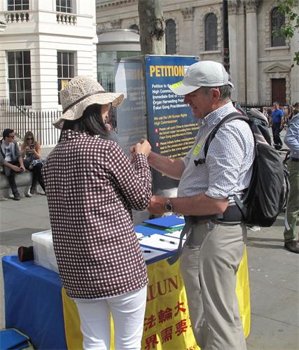图8：二零一八年六月二十三日，在伦敦圣马丁广场，来伦敦参加活动的彼得（Peter）听法轮功学员讲真相，非常高兴地接过法轮功学员送给他的手工莲花。