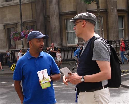 图9：二零一八年六月二十三日，在伦敦圣马丁广场，从比利时安特卫普来伦敦旅游的保罗（Paul，右）与遇到的法轮功学员交谈。