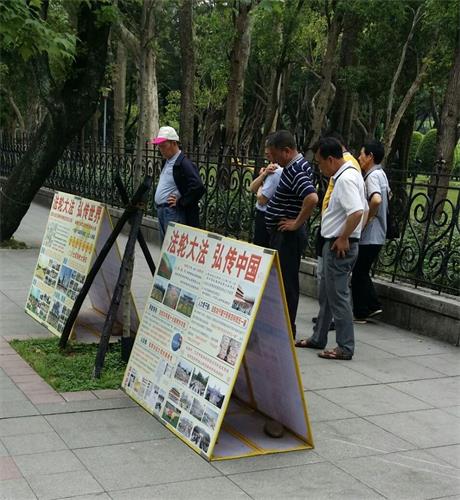'图1～2：游客在台湾台北国父纪念馆前的法轮功真相点上认真阅读展板'